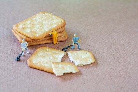 Group of teamwork miniature people, small model human figure cleaning crackers on wooden table Copy space. Teamwork concept.の写真素材