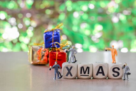 Group of teamwork miniature people, small model human figure standing on alphabet wooden box with green bokeh and copy space. Merry christmas concept.の写真素材