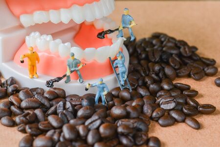 Group of teamwork miniature people, small model human figure cleaning coffee beans and 
denture on wooden table. Copy space. unhealthy beverage for tooth concept.の写真素材