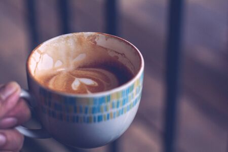 Eatting Hot coffee (espresso, cappuchino, latte) in ceramic white cup in hand with vintage tone, Copy space for your text.の写真素材