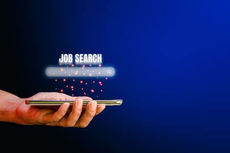 Job search concept. Hand holding smartphone with a search box for looking job on blue background with copy space.の写真素材
