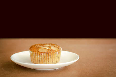 Delicious banana cup cake on white dish and wooden table with copy space. Homemade bakery.の写真素材
