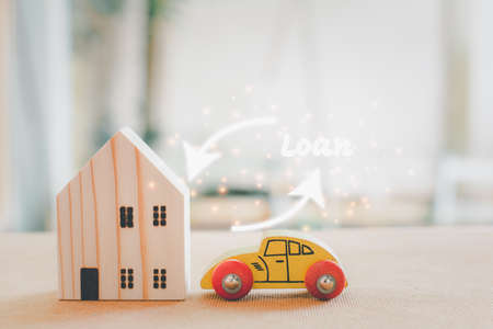 Home and car loan concept. Wooden home and car model with white arrow and loan text.の写真素材