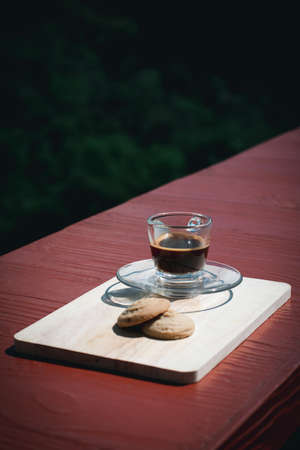 Espresso or black coffee served with butter and vanilla cookies on wooden table with green natural background. Energy drink in the morning concept.の写真素材