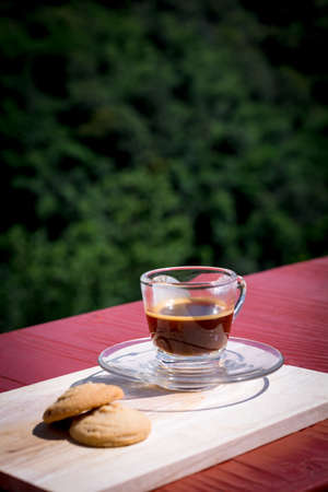 Espresso or black coffee served with butter and vanilla cookies on wooden table with green natural background. Energy drink in the morning concept.の写真素材