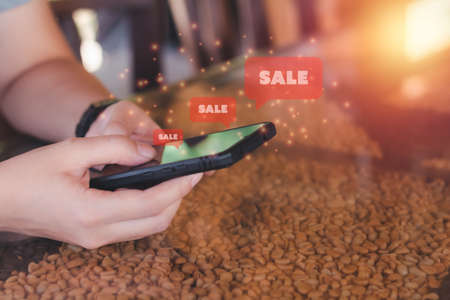 Shopping online concept. Hand holding black smartphone with red popup sale. Black Friday and shop at home.の写真素材