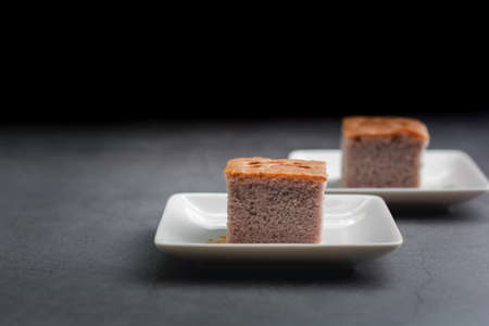 A square-cut of sweet potato cake on a white plate in the kitchen. Bakery and beverage concept.の写真素材