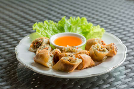 Vegan food concept. Deep-fries cut crispy spring roll with sweet and sour sauce served in a white...