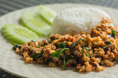 Vegan food concept. Stir-fried Thai basil with minced plant-based, tofu, chili, and mushroom served with rice on a white plate. Famous food of Thailand.の写真素材
