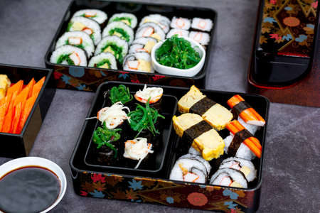 Set of variety sushi, Tamagoyaki, crabsticks sushi and maki in bento box served with soy sauce and wasabi. Delicious japanese food.の写真素材