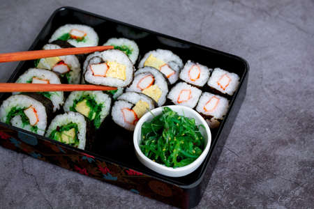 Eatting tamagoyaki maki with wooden chopsticks and soy sauce in white bowl. Delicious japanese food.の写真素材