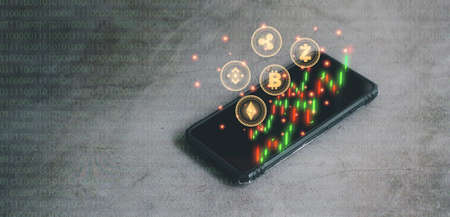 Business and technology concept. Smartphone with cryptocurrency coin with red and green candlestick graph on binary code black background. Big data information exchanges digital currency and online payment.の写真素材