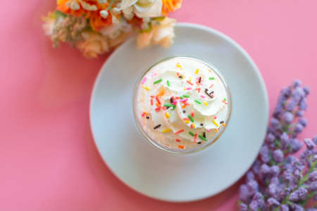 Top view, a bowl of whipping cream with color sugar topping on pink background. Sweet and delicious snack at party concept.の写真素材