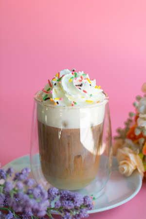 Ice coffee with a layer of milk and whipping cream with color sugar topping on pink background. Beverage and drink at the party concept.の写真素材