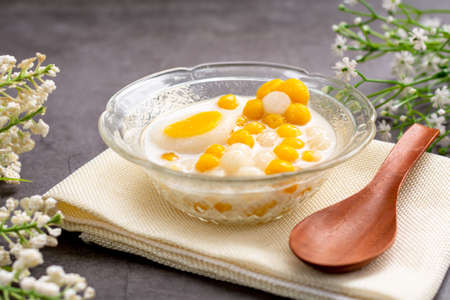 Pumpkin (white and yellow) rice dumpling in coconut milk (Bua Loy) in transparency bowl on wooden table. Delicious Thai dessert.の写真素材