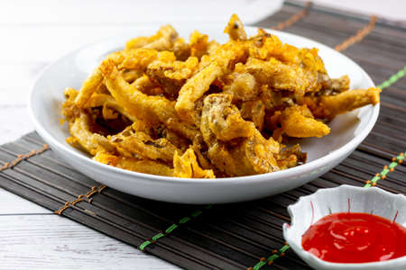 Snack food concept. Deep-fried crispy oyster mushroom on a white plate with red hot chili dipping sauce.の写真素材