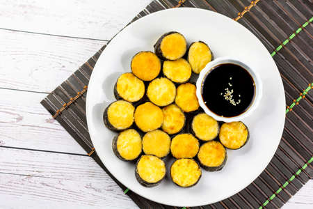 Snack food concept. Deep-fried egg tofu and seaweed wrap on a white plate and soy sauce dipping.の写真素材