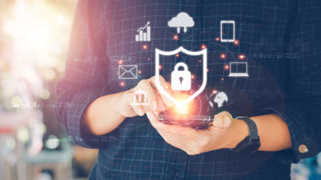 Internet and cybersecurity concept. A businessman is protecting personal data on mobile or smartphone. Online financial errands, data transfer, communication, big data, a virtual lock icon.の写真素材