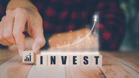 Investment concept. Businessman holding a wooden block and the growth of the graph. Banking and financial, passive income, future returns, growth in assets, and success, save money.の写真素材