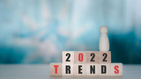 2022 trends concept. Wooden cube block with text 2022 trends and wooden figure. New idea, fashion, popular topic. Business opportunity.の写真素材