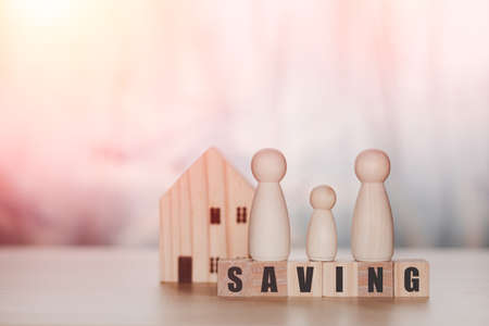 Saving money and financial goals for a family concept. The wooden figure of the family stands on a...