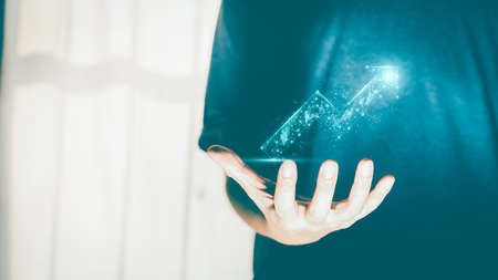 Businessman or trader showing growing virtual hologram or low polygon graph on hand. Strategic planning of business growth, stock market, digital assets, and investment finance.の写真素材