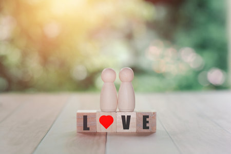 LGBTQ concept. Two wooden figures in love stand together on a wooden block with red hearts. Homosexuality couple.の写真素材