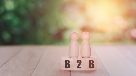 Business to the business concept. Two wooden figure models stand on a wooden block with the text of B2B.の写真素材