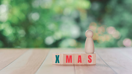 Christmas day concept. A wooden human figure stands on a wooden block with text Xmas.