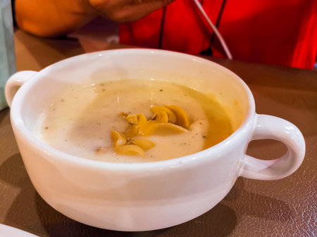 Cream soup mushroom in white ceramic bowl on wooden table in the restaurant.の写真素材