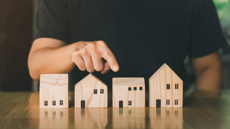 Real estate investment business concept. Businessman pointing finger to wooden model home. Choose and decide for the best house.の写真素材