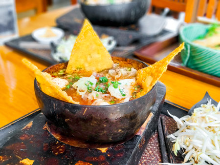 Pink seafood flat noodle in wooden bowl on wooden background. Thailand traditional red tofu sauce...