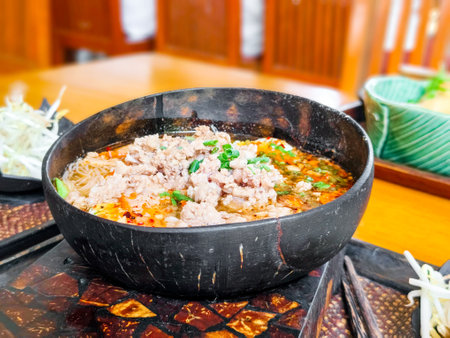 Spicy tom yum noodles with minced pork in wooden bowl. Thai street food concept.の写真素材