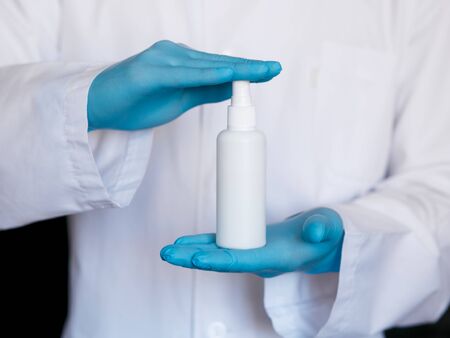 Close up view of female physician hands showing a personal antiseptic or sanitizer. Covid-19 protection measures. Doctor in white medical gown at clean white background.の写真素材