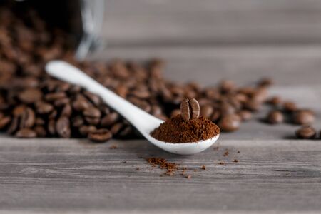 white ceramic spoon with ground coffee on a wooden background Fried Arabica grains.の写真素材