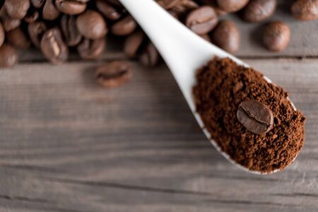 white ceramic spoon with ground coffee on a wooden background Fried Arabica grains.の写真素材