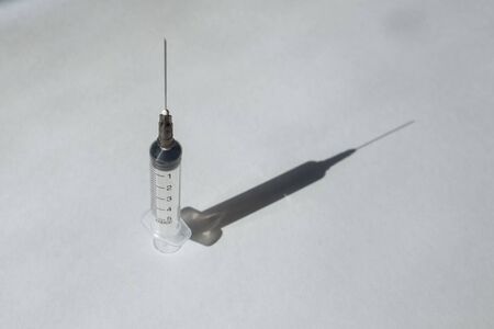 medical syringe with medicine in blue on a white background with a shadowの写真素材