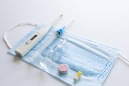 medical mask on cyan, blue background.face mask. mask for diseases. Thermometer and medication. disposable face image. Medical respiratory bandage face. Concept of coronavirus quarantine.の写真素材