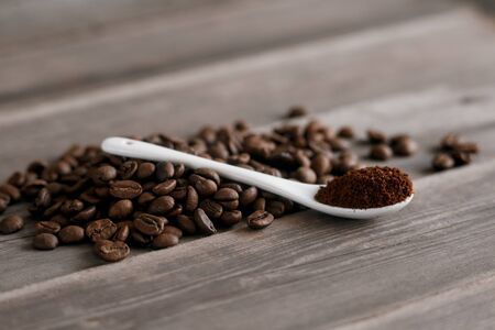  white ceramic spoon with ground coffee on a wooden background Fried Arabica grains.の写真素材