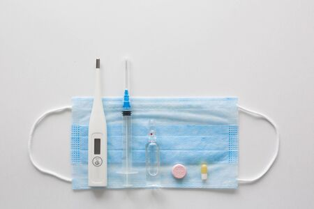 medical mask on cyan, blue background.face mask. mask for diseases. Thermometer and medication. disposable face image. Medical respiratory bandage face. Concept of coronavirus quarantine.の写真素材