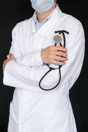 Male Doctor on a black background with a stethoscope in his hands close-up.の写真素材