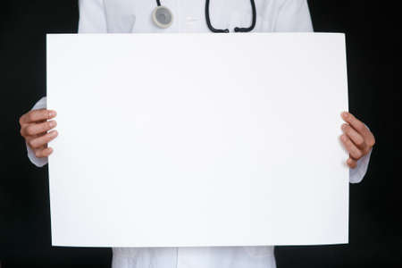 A man in a black t-shirt and medical gloves holds a white sheet of paper. Mockup. Coronavirus. Quarantine . Epidemic. Copy space. Warning. Doctor's hand in blue glove holding sheets of paper.の写真素材
