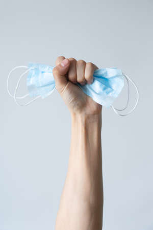 First person view of a woman holding face mask over white table background. Protective raspiratory mask for spreading virus. Close up, copy space, top view, flat layの写真素材