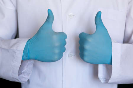 The doctor on a black background in blue medical gloves. Medic shows gesture class.の写真素材