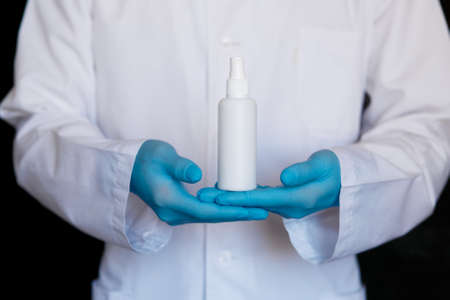 Close up view of female physician hands showing a personal antiseptic or sanitizer. Covid-19 protection measures. Doctor in white medical gown at clean white background.の写真素材