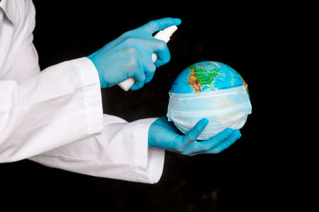The concept is to protect the planet from coronavirus. splash the antiseptic on the globe. Covid-19 and the globe in the hands of the doctorの写真素材