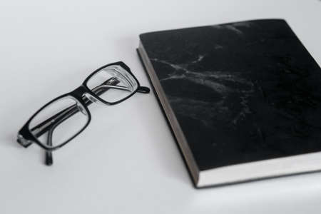 New black leather Notebook diary with black glasses isolated on white backgroundの写真素材