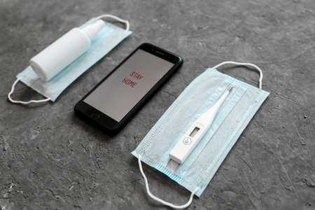 The concept of staying at home is the epidemic of the coronavirus covid-19. Antiseptic face mask medical gloves and phone on a white background. View from above copy space.のeditorial素材