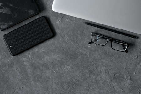smartphone on office desk with laptop and cup of coffee on gray concrete. Business or education concept. Top view with copy space, flat layの写真素材
