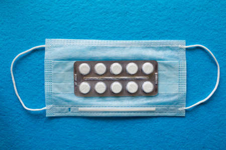 Many Medical mask, Medical protective mask on blue background with Multi-colored tablets. Disposable surgical face mask cover the mouth and nose. Healthcare and medical concept.の写真素材